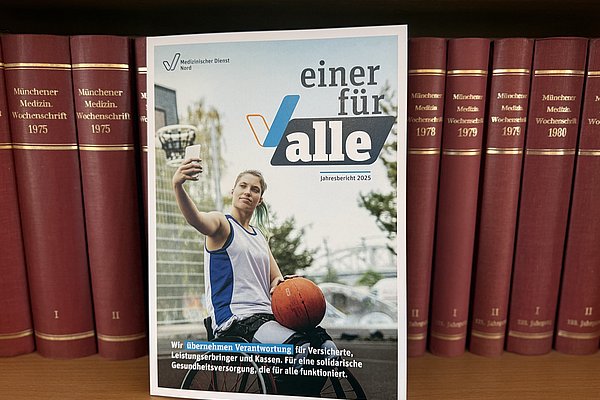 Der Jahresbericht steht vor einem B&uuml;cherregal