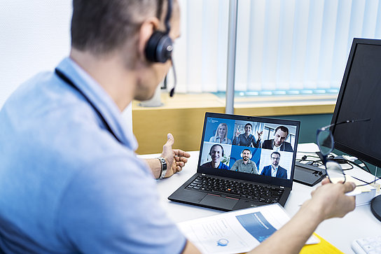 Ein Mann nimmt an einer Videokonferenz teil und ist im Gespräch mit verschiedenen Kolleginnen und Kollegen.